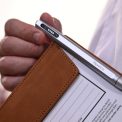 male hand holding clipboard silver pen clipped white shirt